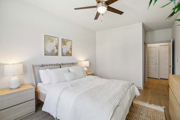 A bedroom with a bed, nightstand, and a ceiling fan. at ThreeTwenty at the Vybe Apartments, Kyle, TX, 78640