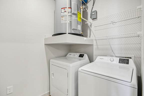 A wall-mounted washer and dryer are installed in a small room. at ThreeTwenty at the Vybe Apartments, Texas
