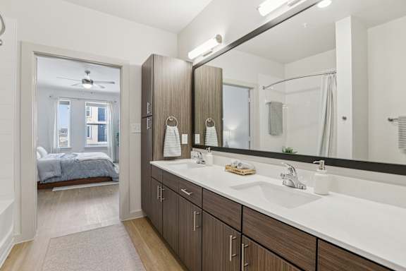A bathroom with a large mirror and a bedroom with a bed and a window. at ThreeTwenty at the Vybe Apartments, Kyle, Texas