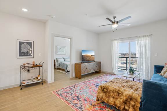 A bedroom with a bed, a chair, and a rug. at ThreeTwenty at the Vybe Apartments, Kyle, TX
