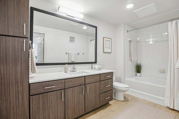 A bathroom with a white toilet, a sink, and a bathtub at ThreeTwenty at the Vybe Apartments, Kyle, TX, 78640
