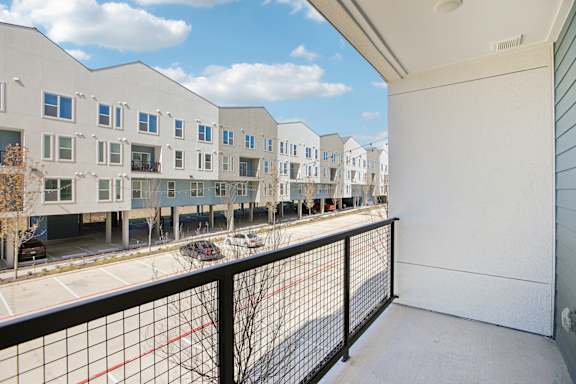 A view of a balcony with a black railing and a red line on the ground at ThreeTwenty at the Vybe Apartments, Kyle, TX