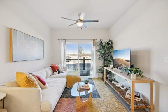 A living room with a white couch, a wooden coffee table, and a flat screen TV. at ThreeTwenty at the Vybe Apartments, Texas, 78640