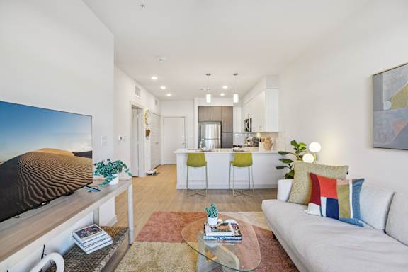 A living room with a white couch, a glass coffee table, and a painting on the wall. at ThreeTwenty at the Vybe Apartments, Kyle, 78640