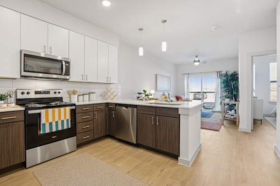 A modern kitchen with wooden cabinets and stainless steel appliances. at ThreeTwenty at the Vybe Apartments, Kyle, TX