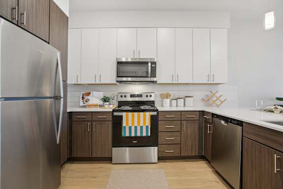 A modern kitchen with a stainless steel refrigerator and a dishwasher at ThreeTwenty at the Vybe Apartments, Kyle