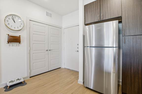 A kitchen with a clock on the wall and a refrigerator at ThreeTwenty at the Vybe Apartments, Kyle