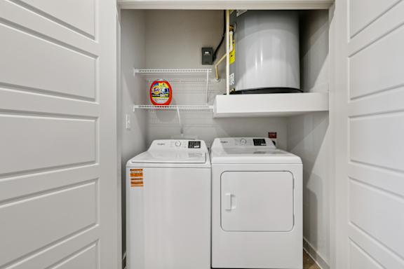 A small laundry room with a washer and dryer at ThreeTwenty at the Vybe Apartments, Kyle, Texas