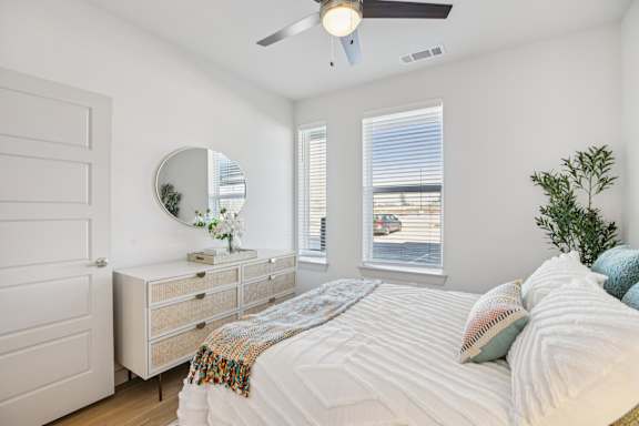 A bedroom with a bed, dresser, mirror, and window at ThreeTwenty at the Vybe Apartments, Texas
