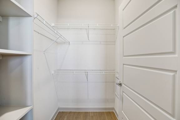 A white closet with shelves and a wooden floor at ThreeTwenty at the Vybe Apartments, Kyle, TX, 78640