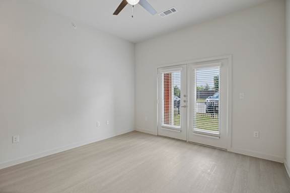 Empty room with french doors and light flooring 1 at Cantarra Apartments, Manor, 78653
