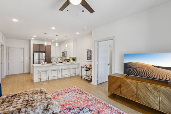 A modern living room with a flat screen TV and a bar area at ThreeTwenty at the Vybe Apartments, Texas