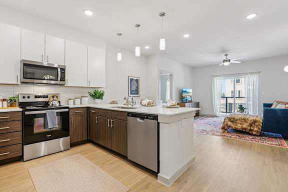 A modern kitchen with stainless steel appliances and wooden cabinets at ThreeTwenty at the Vybe Apartments, Texas, 78640