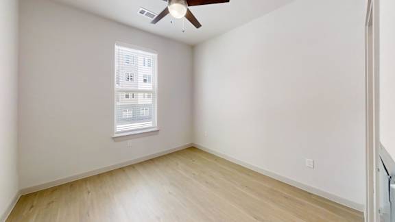 A room with a ceiling fan and a window with blinds.