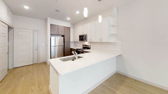 A modern kitchen with a white countertop and wooden flooring.