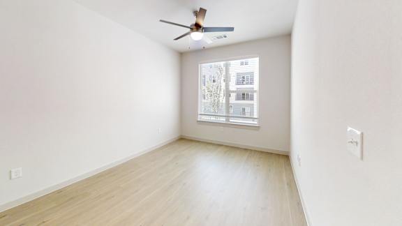 A room with a ceiling fan and a window.