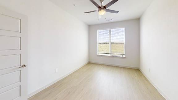 A room with a ceiling fan and a window with blinds.