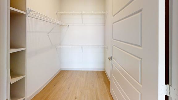 A white pantry with a white door and a white shelf.