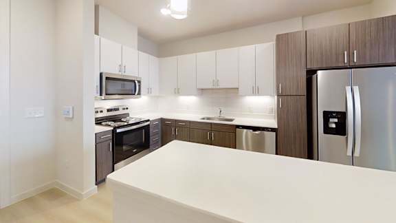 A kitchen with a white counter top and stainless steel appliances.