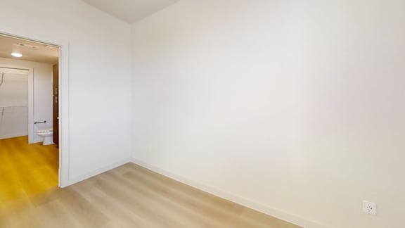 A room with a white wall and wooden floor.