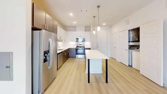 A modern kitchen with a refrigerator, oven, and a table.