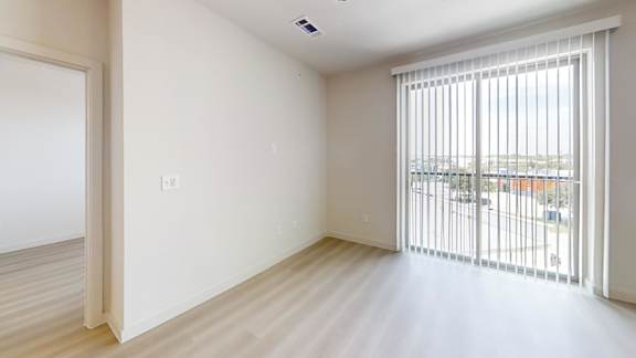 A room with a sliding glass door leading to a balcony.