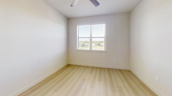 A room with a window and a ceiling fan.