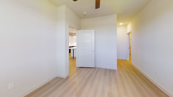 A room with a white door and a ceiling fan.