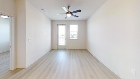 A room with a ceiling fan and a door leading to a balcony.