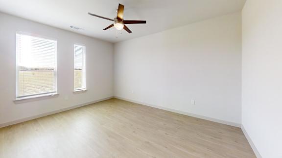 A room with a ceiling fan and two windows.
