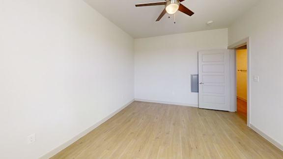 A room with a ceiling fan and wooden flooring.