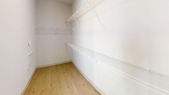 A white wall with a wooden floor and a white shelf.