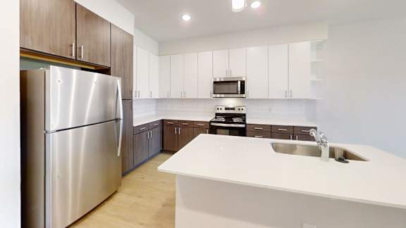 A modern kitchen with a stainless steel refrigerator and white countertops.