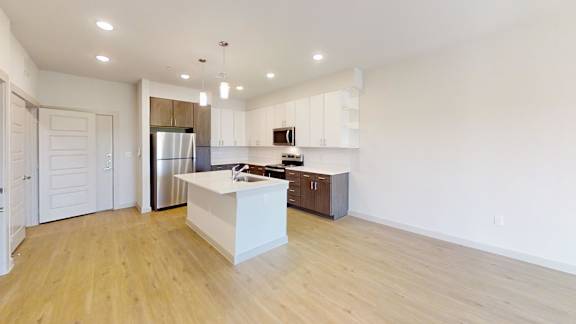 A kitchen with a white island and wooden floors.