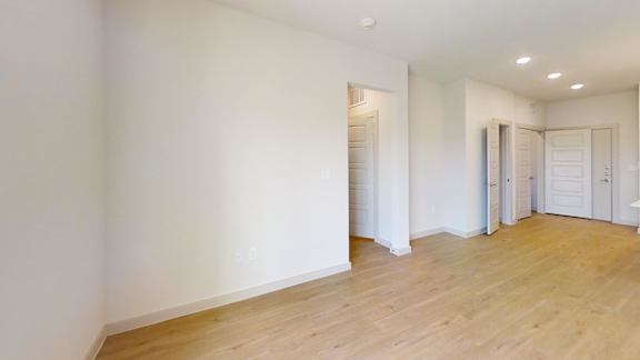 A large empty room with wooden floors and white walls.