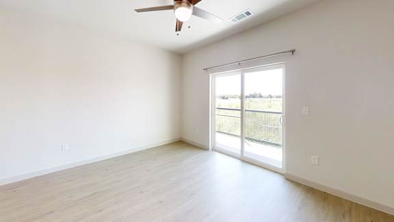 A room with a ceiling fan and sliding glass doors.