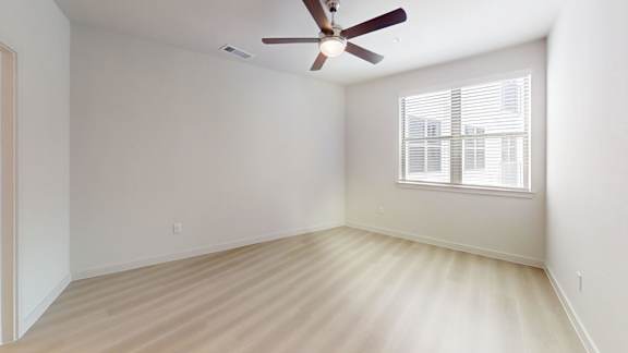 A room with a ceiling fan and a window with blinds.