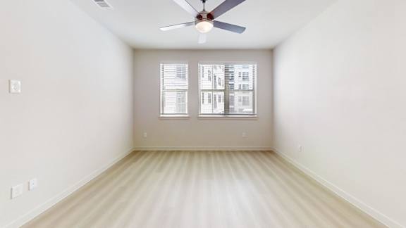 A room with a ceiling fan and a window with blinds.