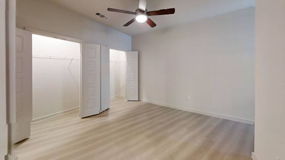 A room with a ceiling fan and white walls.