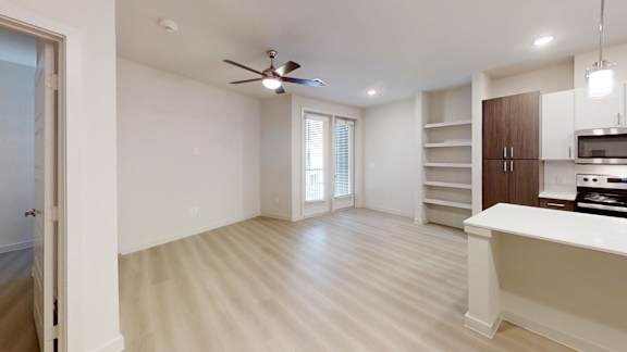 A spacious room with a ceiling fan and a kitchenette.