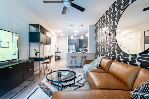 a living room with a brown leather couch and a glass coffee table