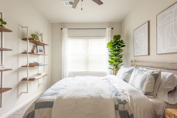a bedroom with white walls and a white bed with a blue and white comforter