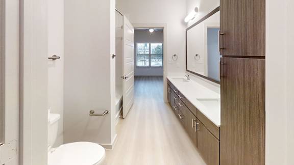 A bathroom with a toilet, sink, and mirror. at Bridge at Saffron Apartments, Austin, Texas