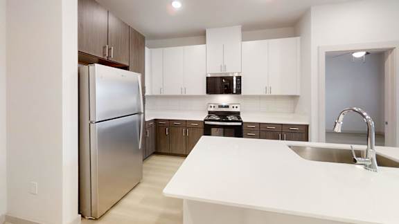 A modern kitchen with a stainless steel refrigerator and white countertops. at Bridge at Saffron Apartments, Texas, 78717