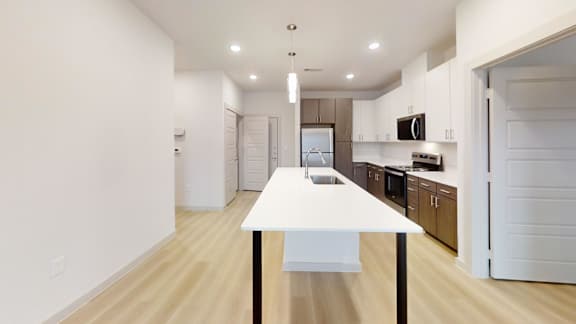 A white table with a black base is in the middle of a room with wooden floors and white walls. at Bridge at Saffron Apartments, Texas