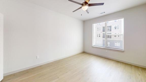 A room with a ceiling fan and a window with blinds.