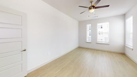 A room with a ceiling fan and a door with a window.