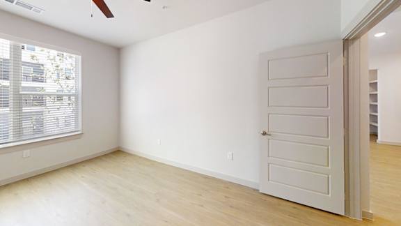A room with a white door and a window with blinds.