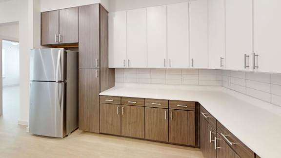 A kitchen with a refrigerator, cabinets, and a counter.