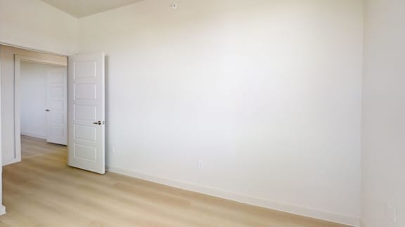 A white room with a door and a wooden floor.